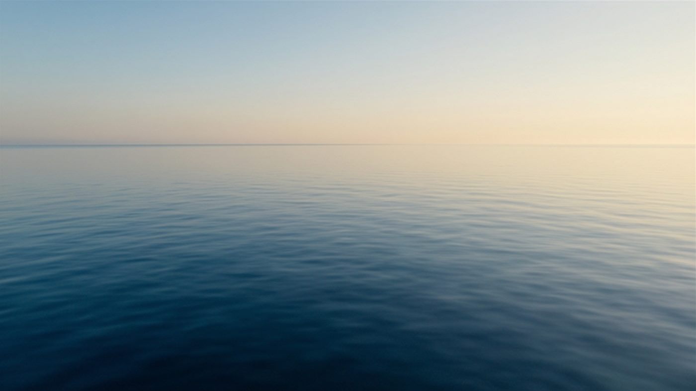 A calm sea meeting a pale dawn horizon